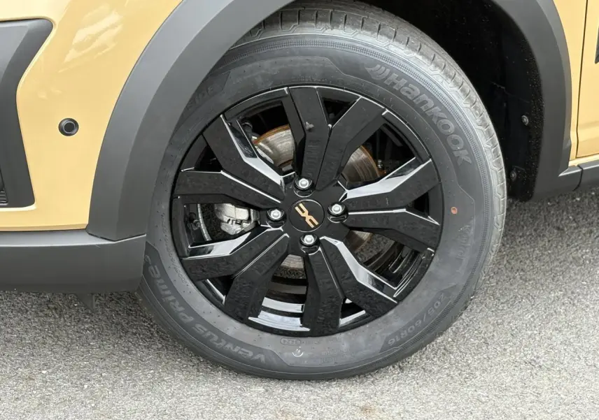 Gros plan sur la roue avant droite noire brillante de la Dacia Sandero Stepway Beige Safari avec jante alu 16 pouces.