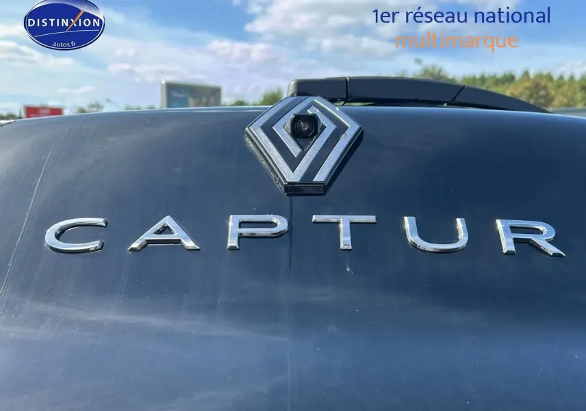 Gros plan sur le logo Renault et l’inscription Captur en chrome sur la malle arrière noire étoile du véhicule.