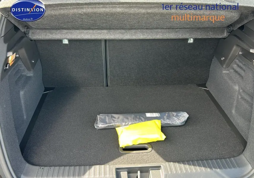 Coffre ouvert vu de l'arrière du Renault Captur noir Étoile, montrant un tapis noir et deux objets emballés.