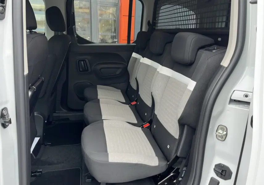 Vue latérale intérieure du Citroën Berlingo Kaolin white montrant les trois sièges arrière indépendants et la grille de séparation.