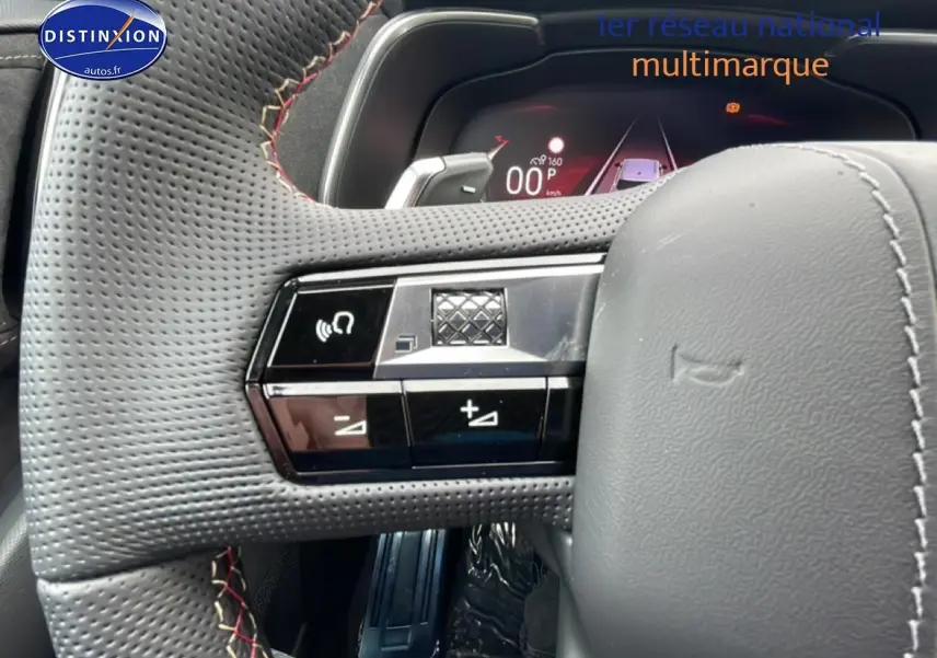 Gros plan sur le volant cuir perforé côté gauche du DS7 noir avec commandes intégrées et palettes au volant.