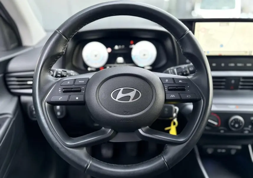 Vue rapprochée du volant cuir noir de la Hyundai i20 2025 avec commandes intégrées et tableau de bord numérique.