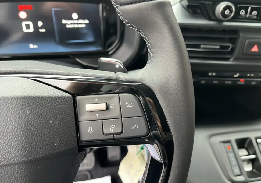 Gros plan sur le volant cuir multifonctions noir du Citroën Berlingo Kaolin White 2026 avec commandes intégrées.