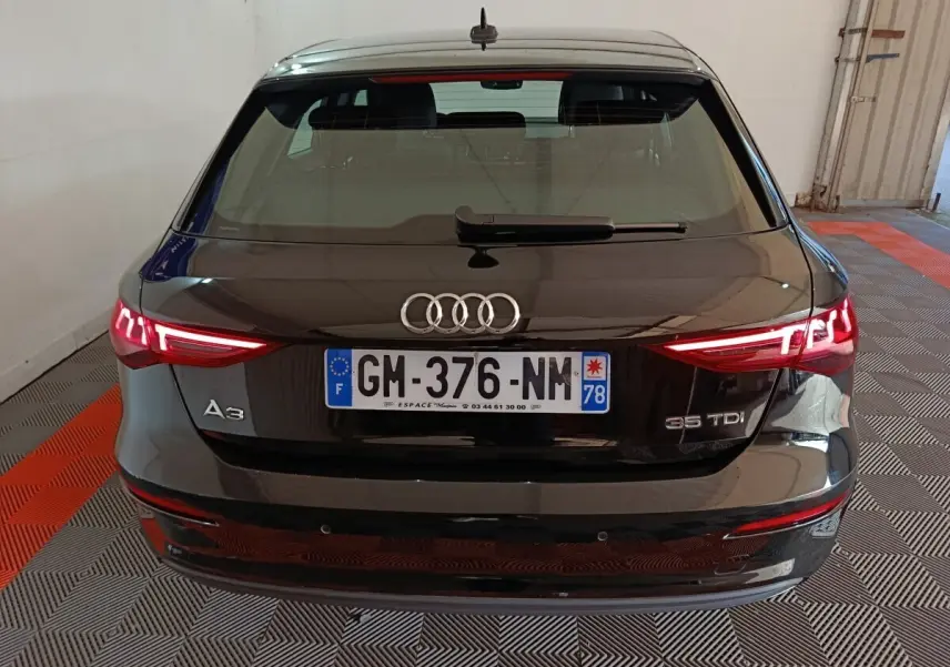 Vue arrière d'une Audi A3 35 TDI noire avec feux LED allumés dans un garage fermé.