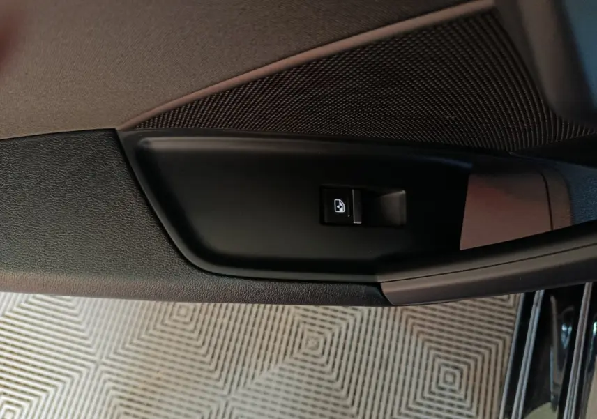 Gros plan sur le bouton de commande de la vitre côté gauche de la porte intérieure noire d’une Audi A3 35 TDI 2023.