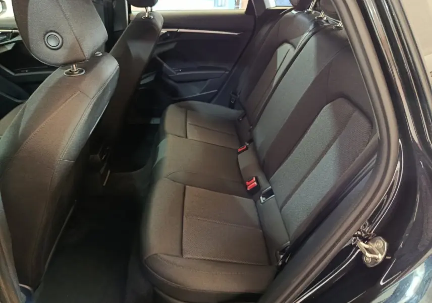 Vue intérieure côté droit sur la banquette arrière noire de l'Audi A3 35 TDI 2023 avec sièges tissu et ceintures rouges.