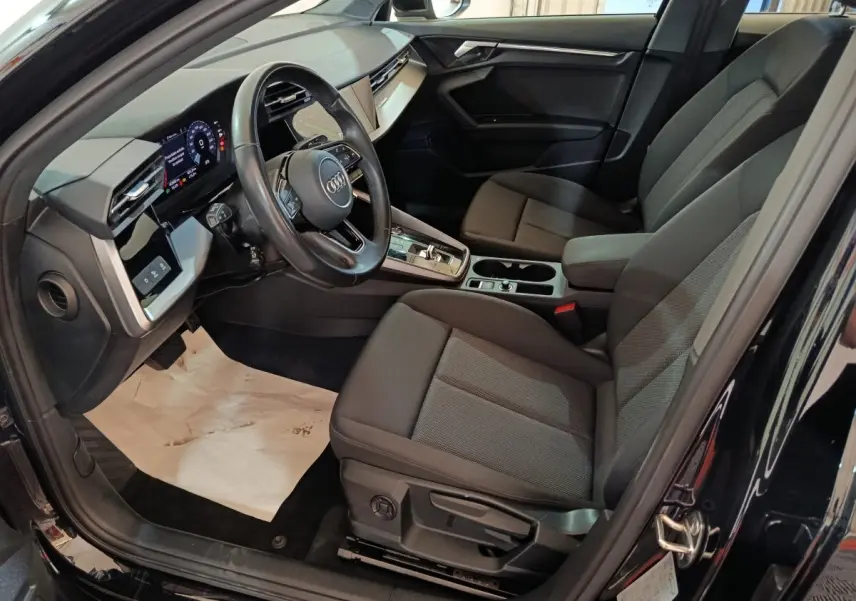 Vue intérieure côté conducteur de l'Audi A3 35 TDI noire, avec tableau de bord digital et sièges tissu gris.