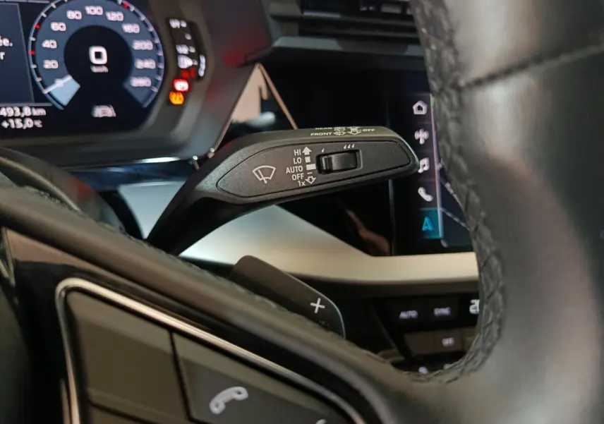 Gros plan sur la manette d’essuie-glace à gauche du volant cuir noir de l’Audi A3 35 TDI 2023 avec tableau de bord digital.