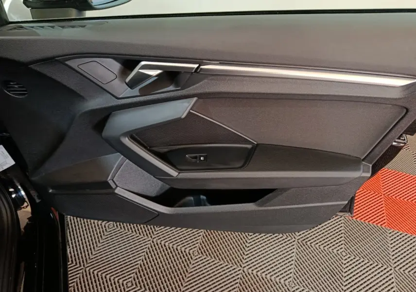 Vue intérieure côté gauche de la porte noire d’une Audi A3 35 TDI 150 S tronic Business Line avec poignée argentée.