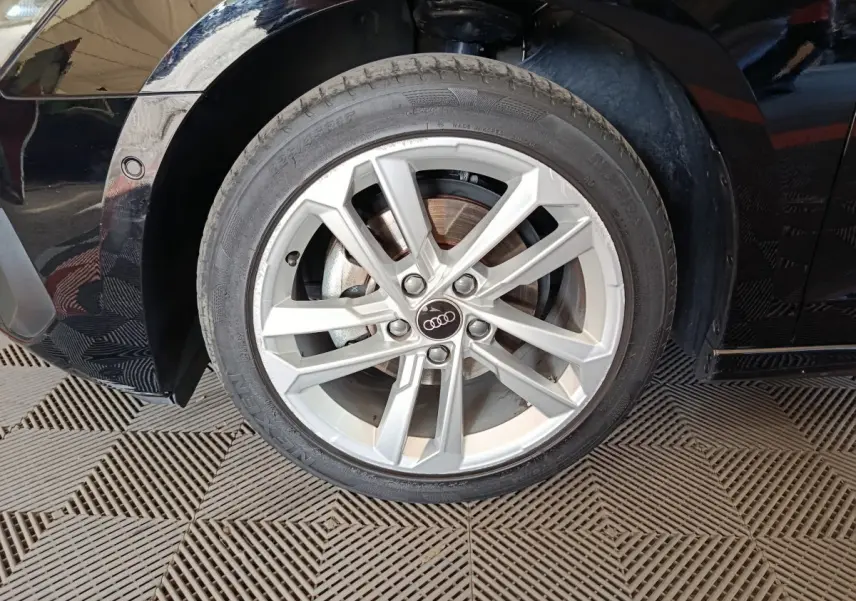 Gros plan sur la roue avant droite d’une Audi A3 noire 2023 avec jante en alliage argentée et logo Audi central.