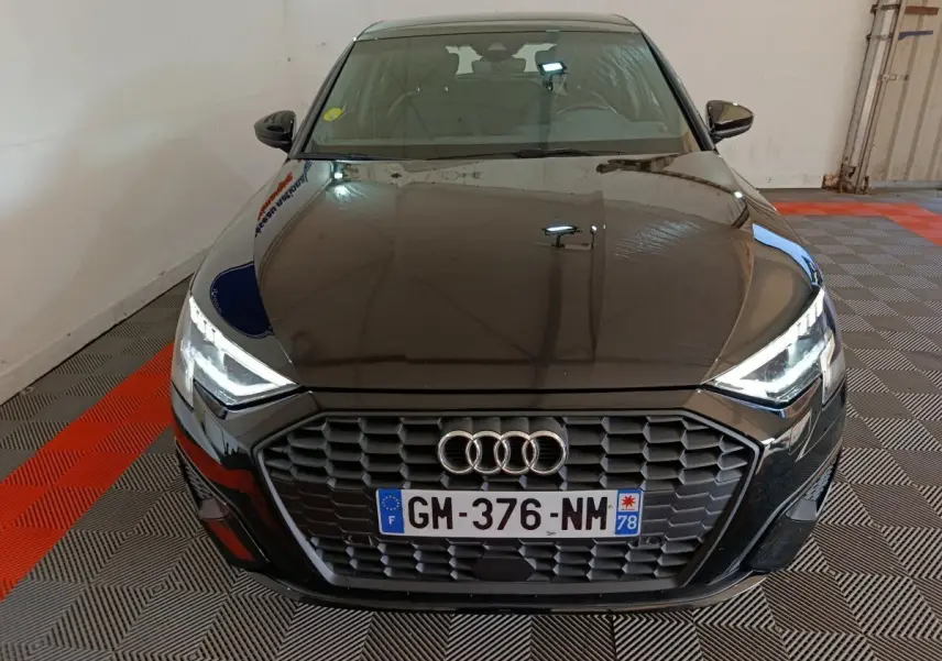 Vue avant d’une Audi A3 35 TDI noire avec calandre hexagonale et phares LED allumés dans un garage.