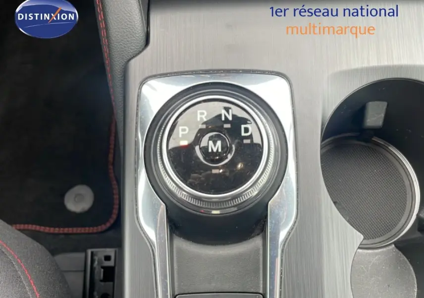 Vue intérieure en gros plan sur la molette de boîte automatique du Ford Kuga 2024, finition ST-LINE, avec console grise et porte-gobelet.