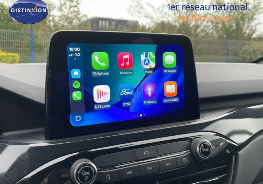 Écran tactile central du Ford Kuga 2024 affichant les applications, avec tableau de bord en finition noire brillante.