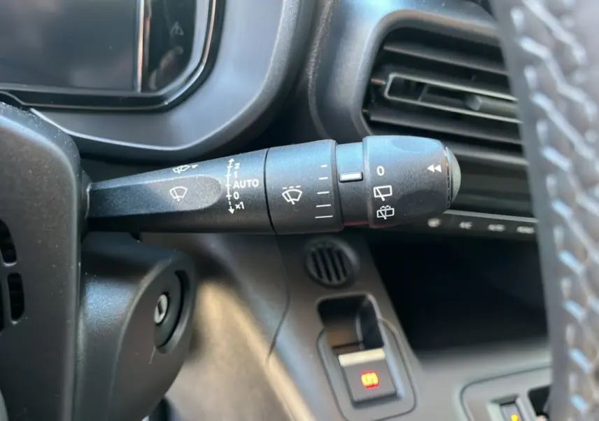 Gros plan sur la commande d’essuie-glace à gauche du volant dans l’habitacle du Citroën Berlingo gris artense.