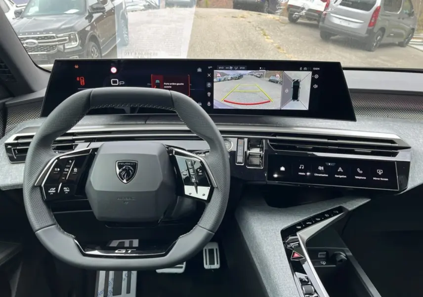Vue intérieure du tableau de bord du Peugeot 3008 Hybrid 145 GT Alcantara avec volant cuir et écrans digitaux larges.