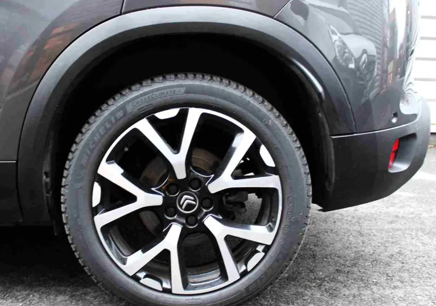 Gros plan sur la roue arrière droite du Citroën C5 Aircross gris platinium, avec jante alliage bicolore distinctive.