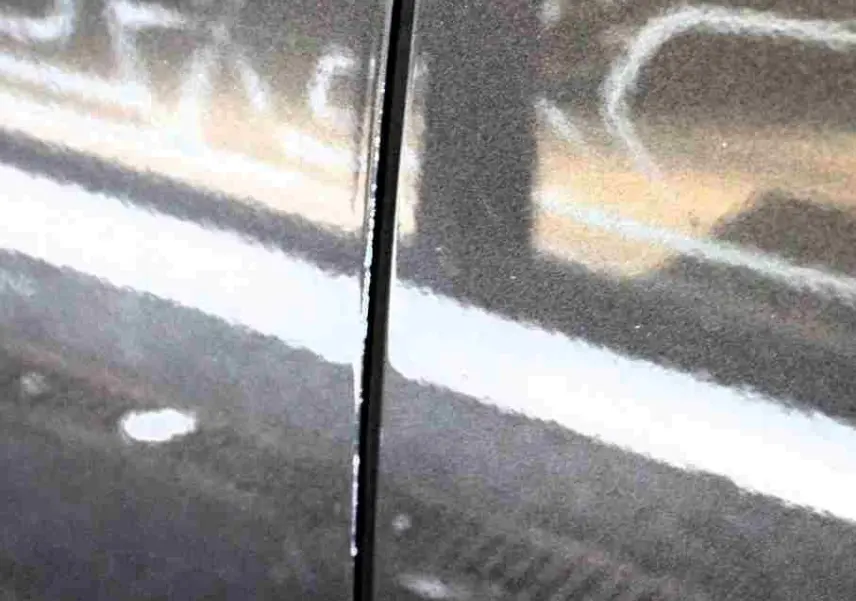 Gros plan sur la jonction entre deux panneaux latéraux du Citroën C5 Aircross gris platinium, reflet flou d’un autre véhicule visible.