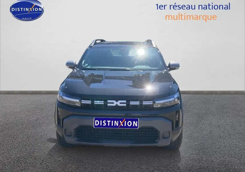 Vue avant d'un Dacia Duster noir 2025 avec calandre moderne et phares LED fins allumés.