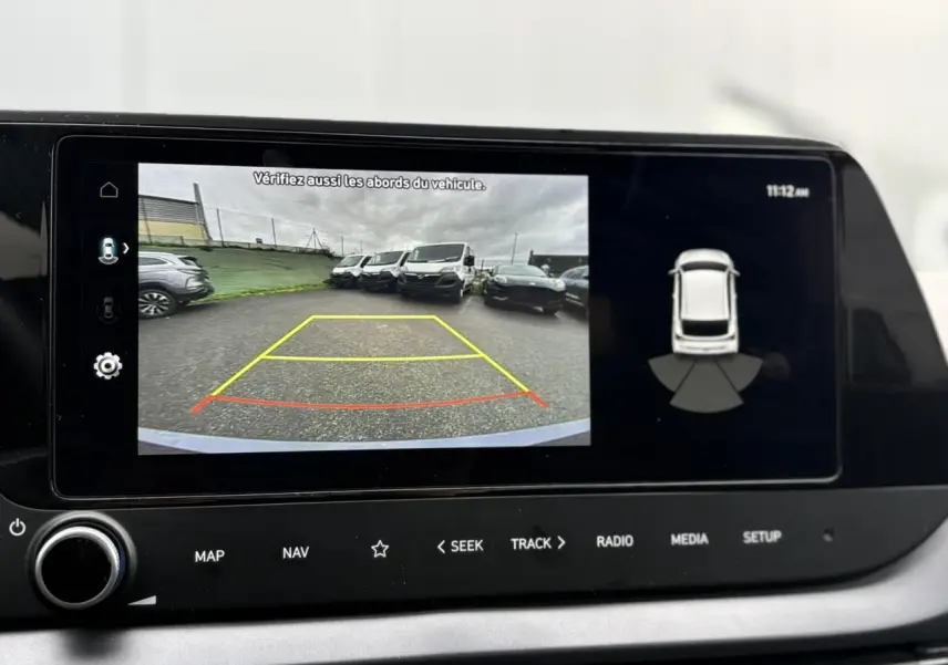 Écran tactile intérieur montrant la caméra de recul et l'affichage du système d'aide au stationnement du Hyundai i20 gris Aurora Metal.