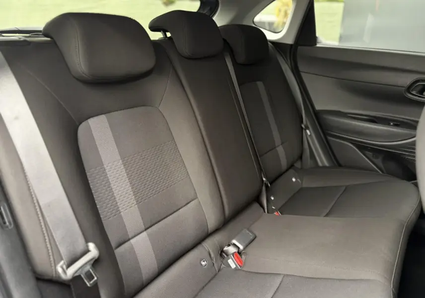 Vue intérieure des sièges arrière noirs de la Hyundai i20 2025, avec ceinture de sécurité et porte latéral visible.