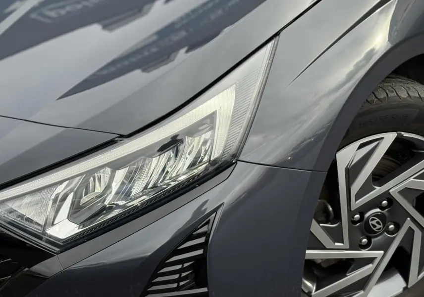 Gros plan sur l'avant droit de la Hyundai i20 2025 gris Aurora Metal, mettant en valeur le phare LED et la jante alliage diamantée.