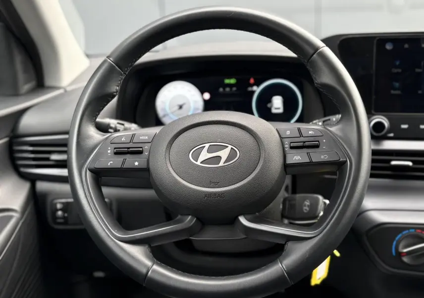 Vue rapprochée du volant cuir noir de la Hyundai i20 2025 avec commandes intégrées et tableau de bord numérique.