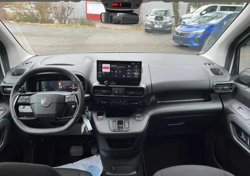 Vue intérieure frontale du tableau de bord noir du Citroën Berlingo Kaolin White avec écran tactile et volant multifonctions.
