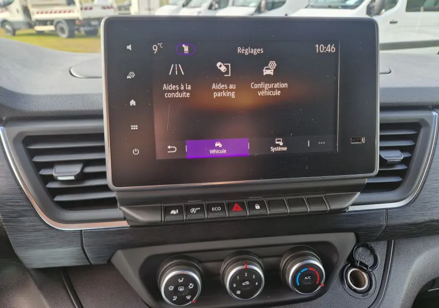 Vue rapprochée de l’écran tactile central et des commandes de climatisation du Nissan Primastar gris urbain, version 2025.