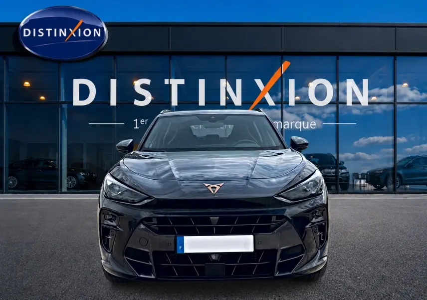 Vue frontale d'un CUPRA TERRAMAR gris Timanfaya avec logo cuivré, devant une vitrine Distinxion.