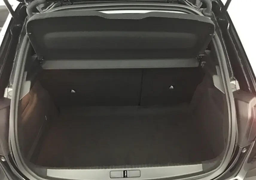 Coffre ouvert de la Peugeot 208 noire 2022, vue plongeante montrant l'espace de rangement vide et propre.