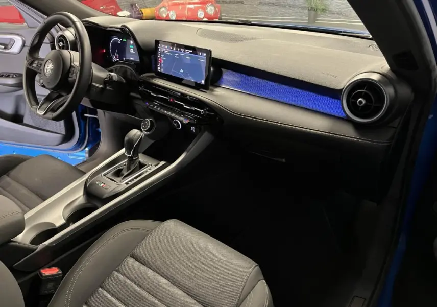 Intérieur avant droit de l'Alfa Romeo Tonale bleu 2024, avec tableau de bord digital et éclairage d'ambiance bleu.