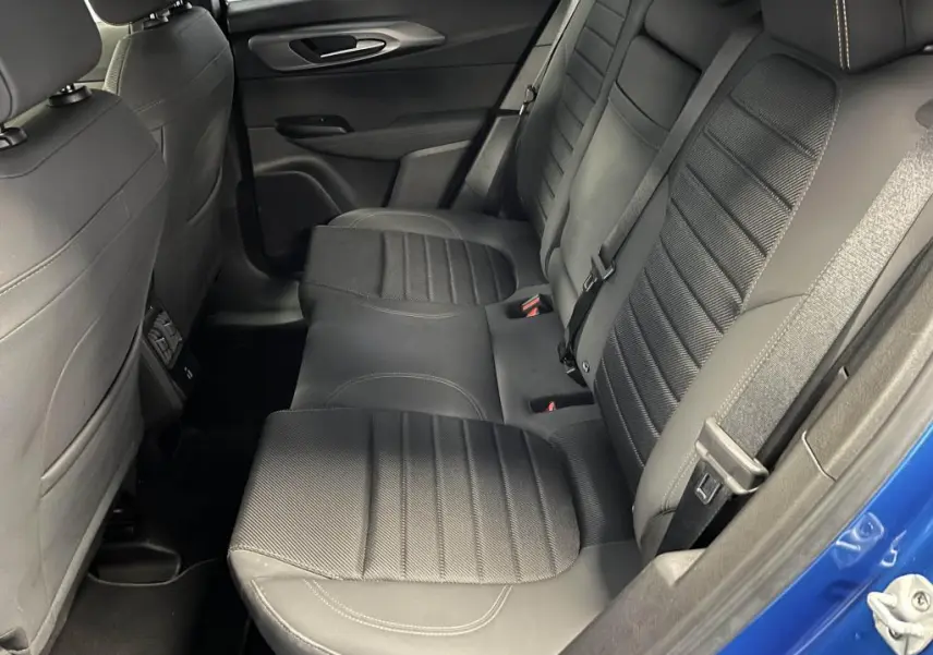 Vue latérale des sièges arrière noirs en tissu AlfaTec avec surpiqûres beige de l'Alfa Romeo Tonale bleu 2024.