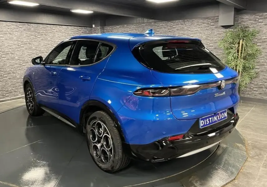 Vue 3/4 arrière droite d'un Alfa Romeo Tonale bleu métallisé avec jantes 18 pouces et antenne aileron de requin.