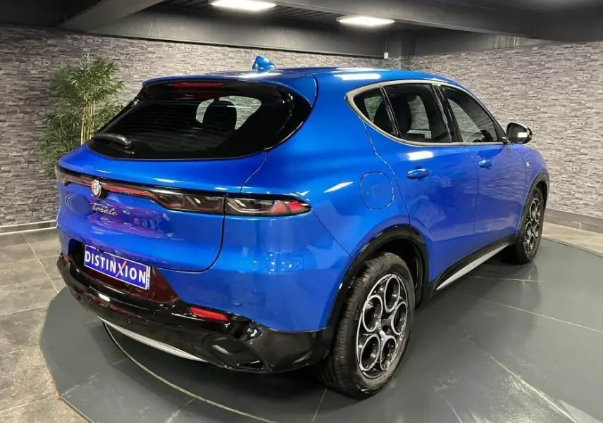 Vue 3/4 arrière droite d'une Alfa Romeo Tonale bleu métallisé avec jantes 18 pouces et toit noir brillant.