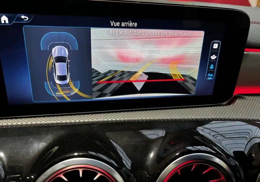 Écran tactile intérieur montrant l’aide au stationnement arrière de la Mercedes CLA 250 e AMG Line blanche.
