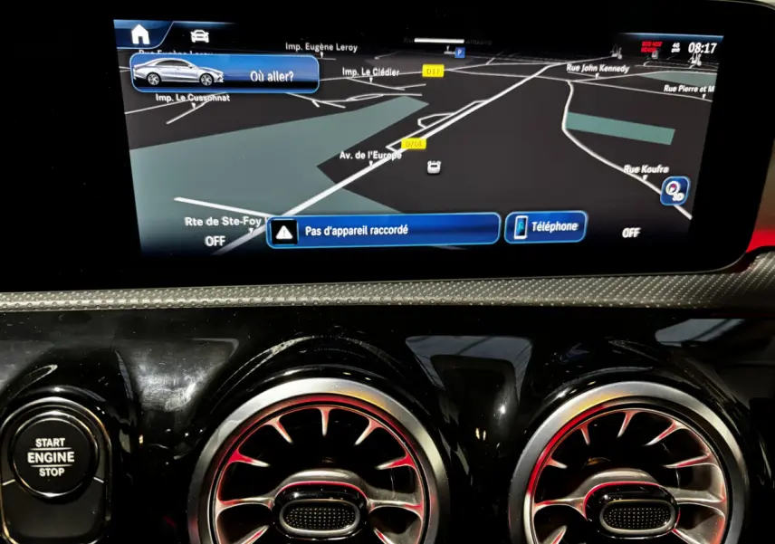 Tableau de bord de Mercedes CLA 250 e AMG Line 2023 avec écran tactile navigation et aérateurs ronds au design métallique rouge.