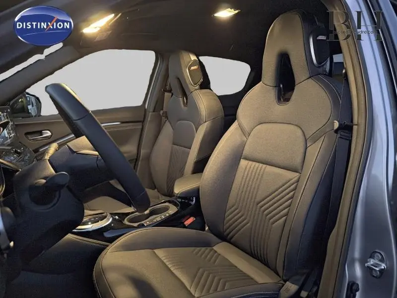 Vue intérieure côté conducteur du Nissan Juke 1.6 Hybrid 2025 avec sièges sport noirs et détails gris perle métallisé.