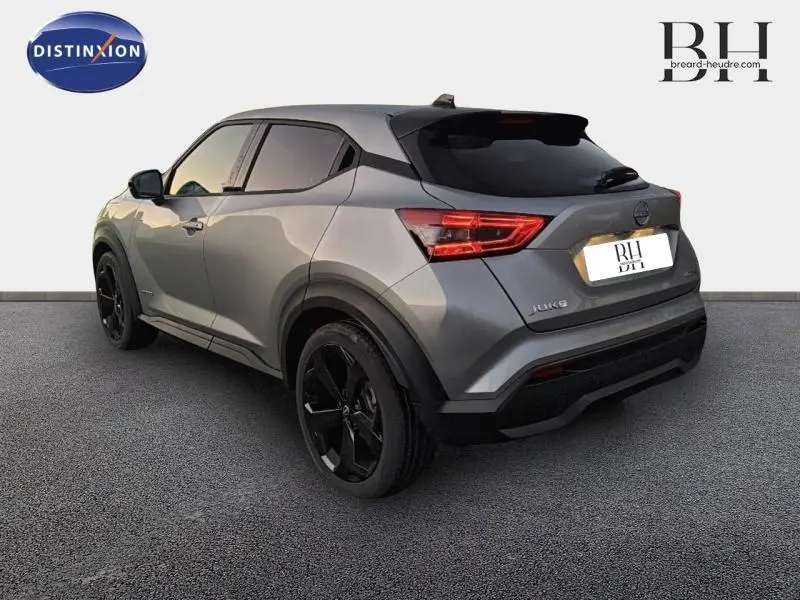 Vue 3/4 arrière droite du Nissan Juke 1.6 Hybrid Tekna 2025 en gris perle métallisé avec jantes noires distinctives.
