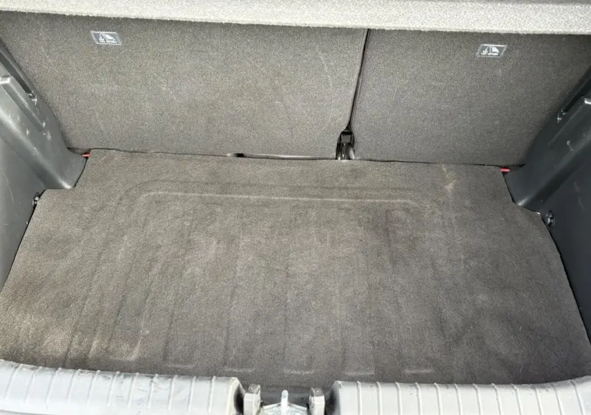 Coffre ouvert vu de l'arrière d'une Hyundai i20 Rouge Dragon Metal, montrant le tapis de coffre et banquette arrière.