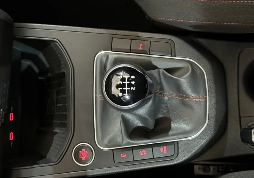 Vue rapprochée du levier de vitesse manuel noir avec coutures rouges dans une SEAT Ibiza blanche 2024.