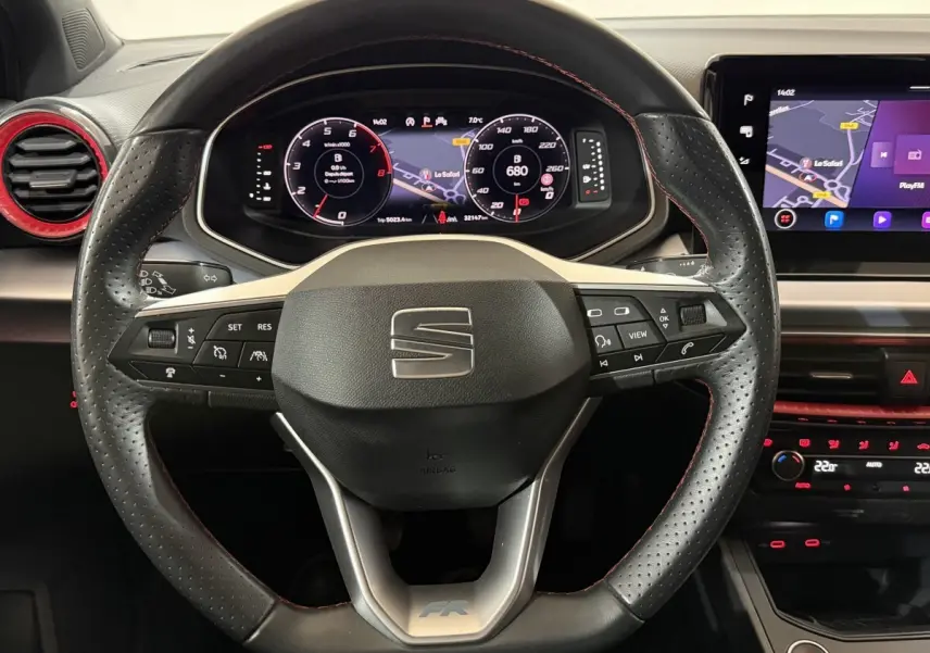 Vue intérieure centrée sur le volant cuir perforé avec logo SEAT et tableau de bord numérique de la Ibiza 1.0 TSI 110 FR.