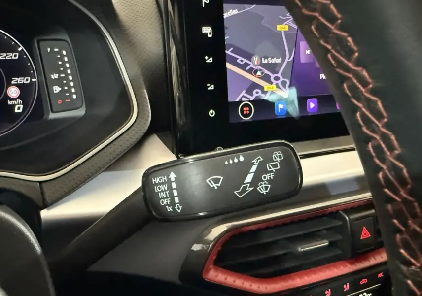 Gros plan sur la commande des essuie-glaces et l’écran tactile de navigation dans l’habitacle de la SEAT Ibiza blanche 2024.