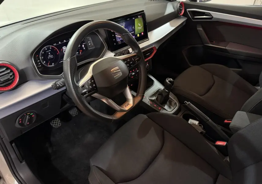 Vue intérieure côté conducteur de la SEAT IBIZA 1.0 TSI 110 FR avec volant cuir, écran tactile et levier de vitesses manuel.