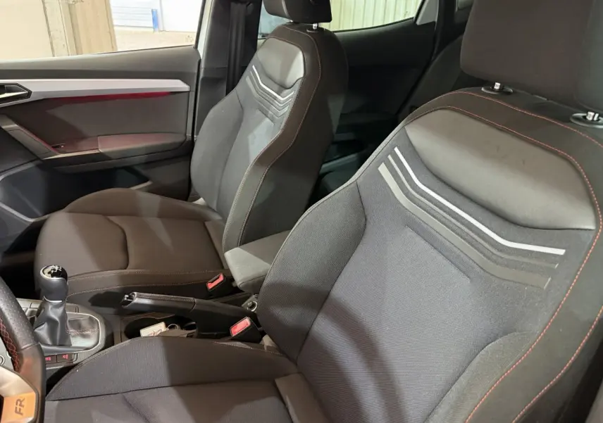 Vue intérieure rapprochée des sièges avant noirs avec surpiqûres rouges et levier de vitesse manuel d'une SEAT Ibiza 2024.