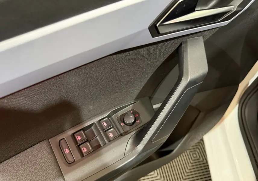 Gros plan sur la commande des vitres et rétroviseurs côté conducteur d’une SEAT Ibiza blanche, porte ouverte.