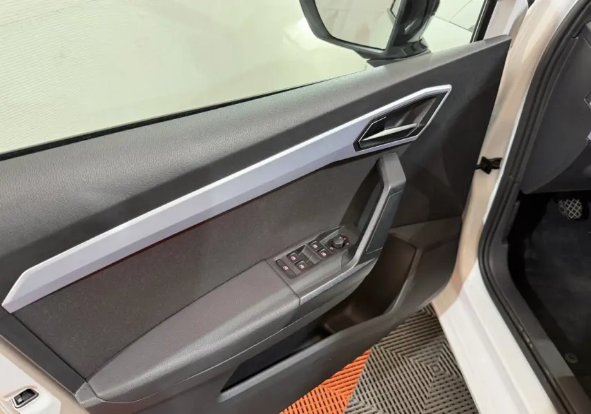 Vue intérieure côté gauche de la porte avant blanche d'une SEAT Ibiza 2024 avec commandes électriques et poignée angulaire.