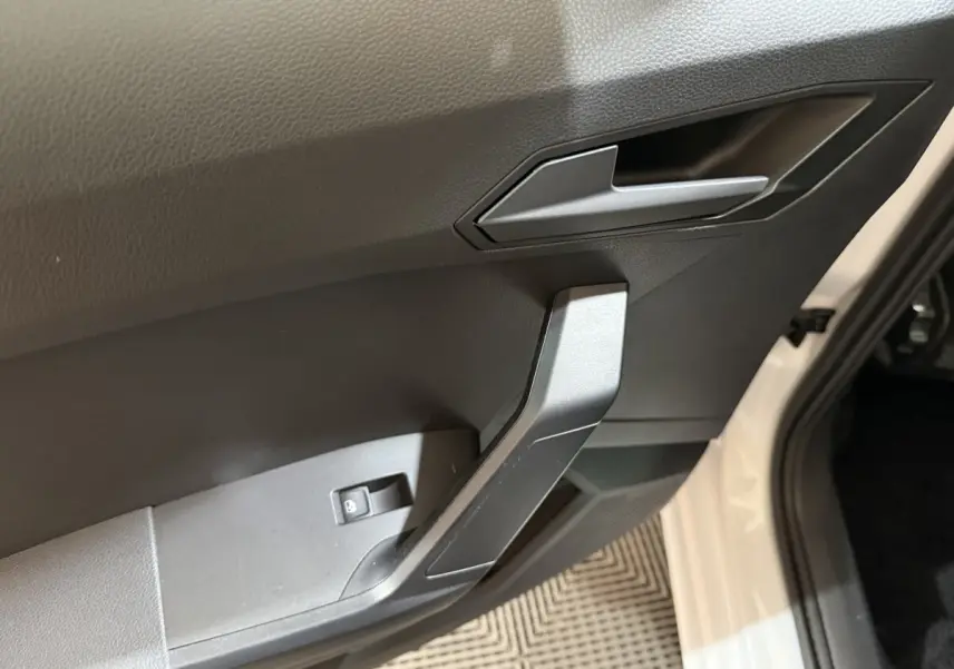 Détail de la poignée intérieure côté conducteur d’une SEAT Ibiza 2024 blanche, avec bouton de verrouillage des vitres.