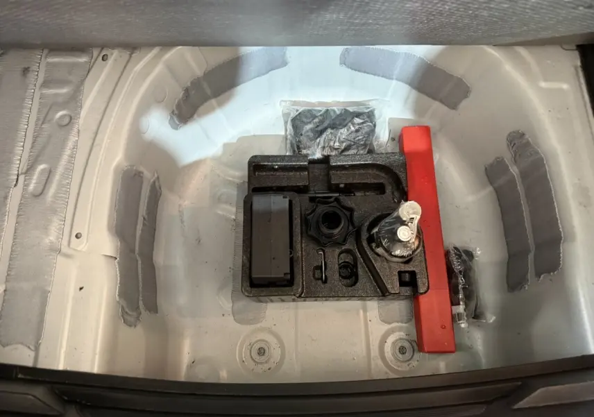 Vue plongeante sur le coffre blanc d'une SEAT IBIZA 2024, montrant le rangement sous plancher avec kit de réparation pneus.
