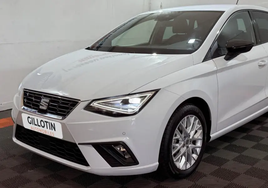 Vue 3/4 avant droit d'une SEAT Ibiza blanche avec phares LED et jantes alliage multibranches.