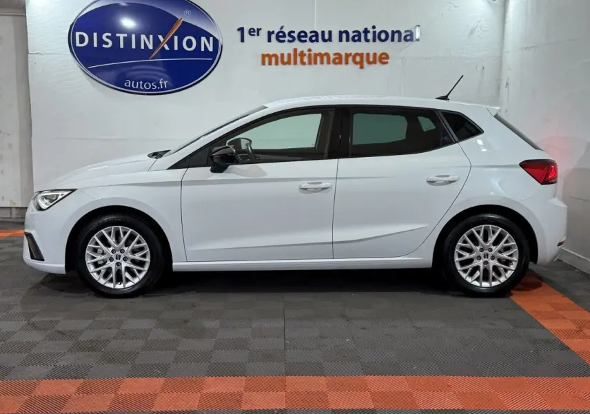 Vue latérale droite d'une SEAT Ibiza blanche 2024, avec jantes alliage et rétroviseurs noirs dans un showroom.